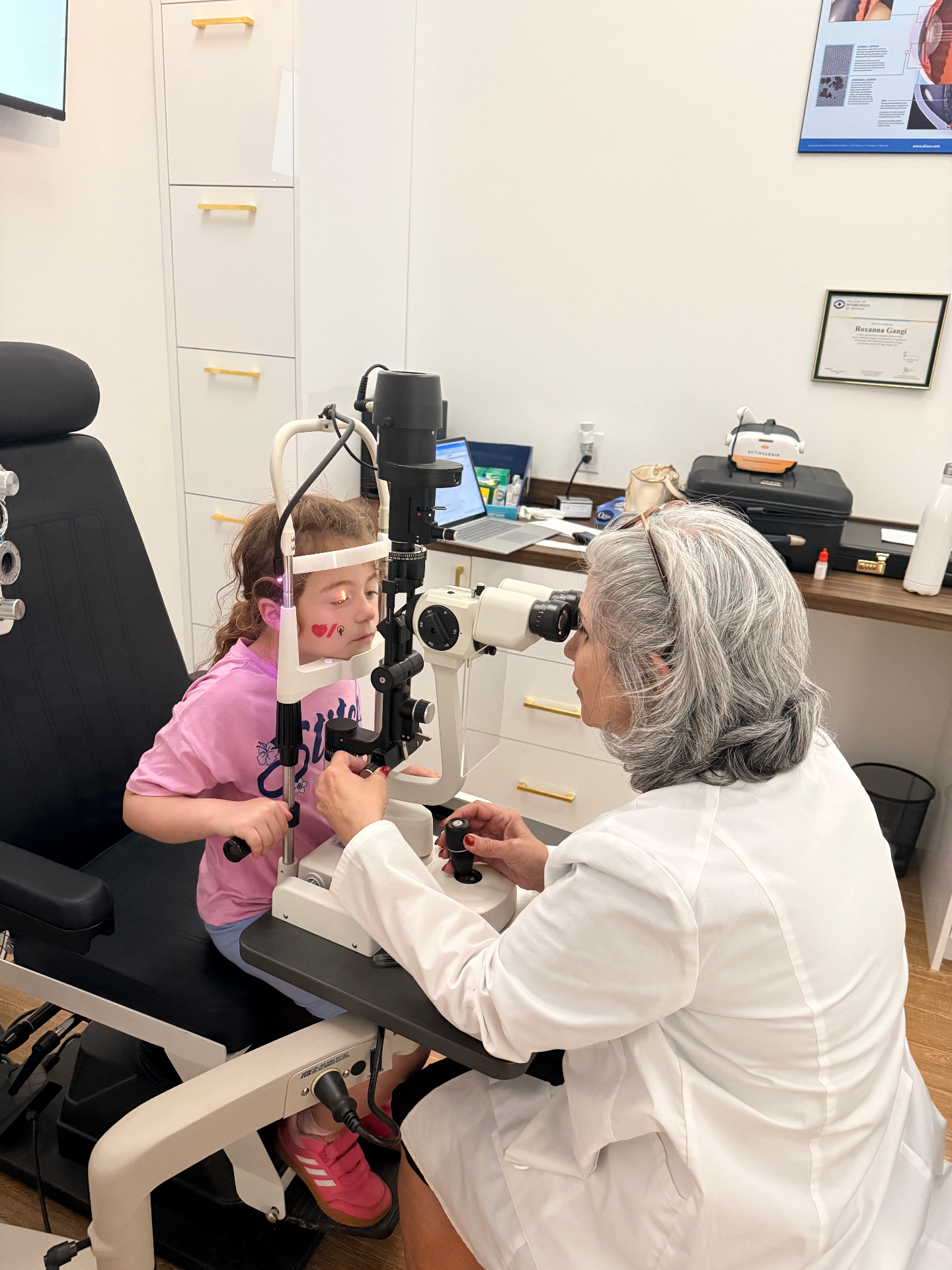 Dr. Roxanna Gangi performing a slit lamp eye exam on a young child as part of a comprehensive children's eye exam and myopia management evaluation