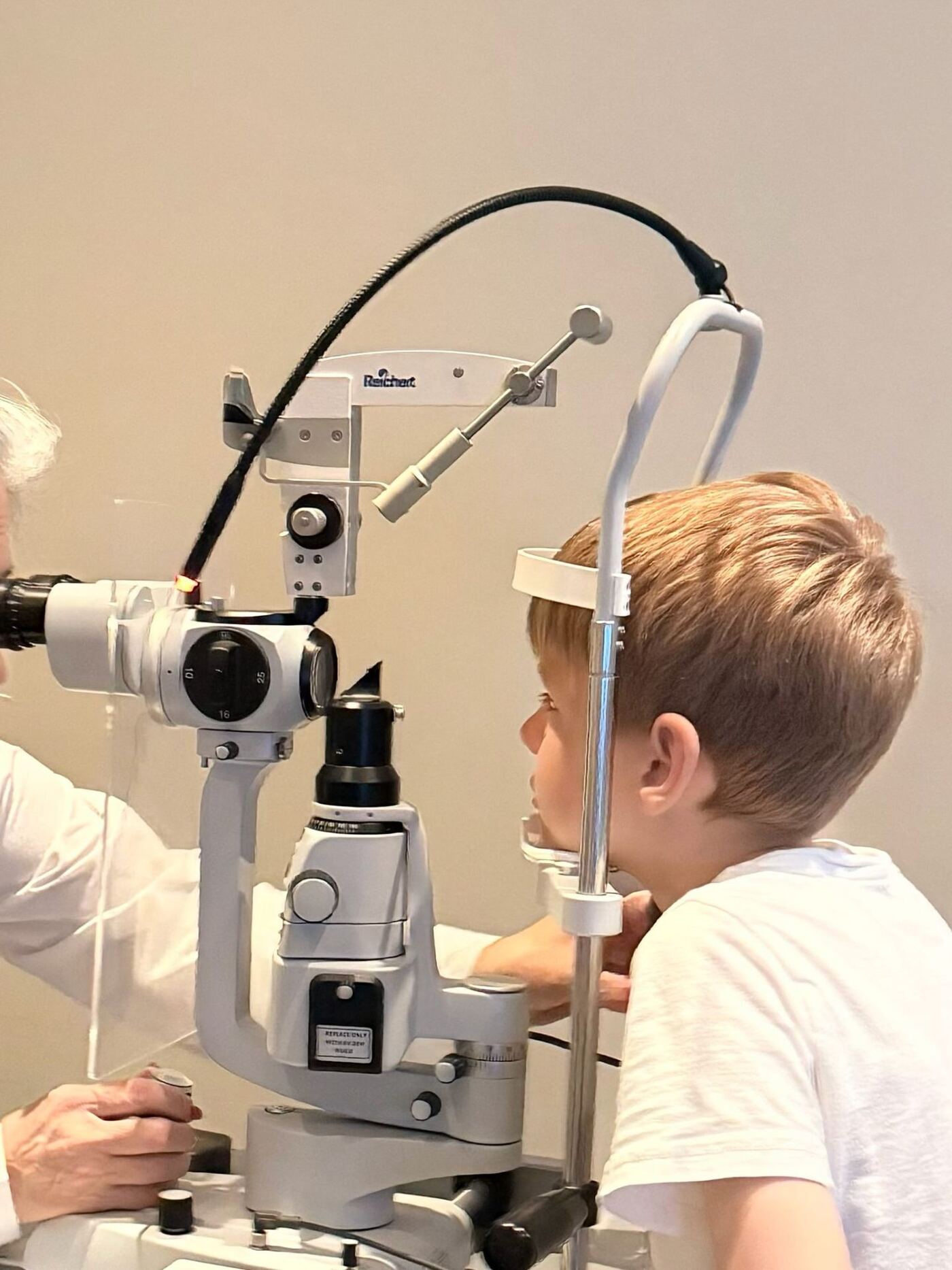 Dr. Roxanna Gangi examines a young boy's eyes with a slit lamp during a children's eye exam.