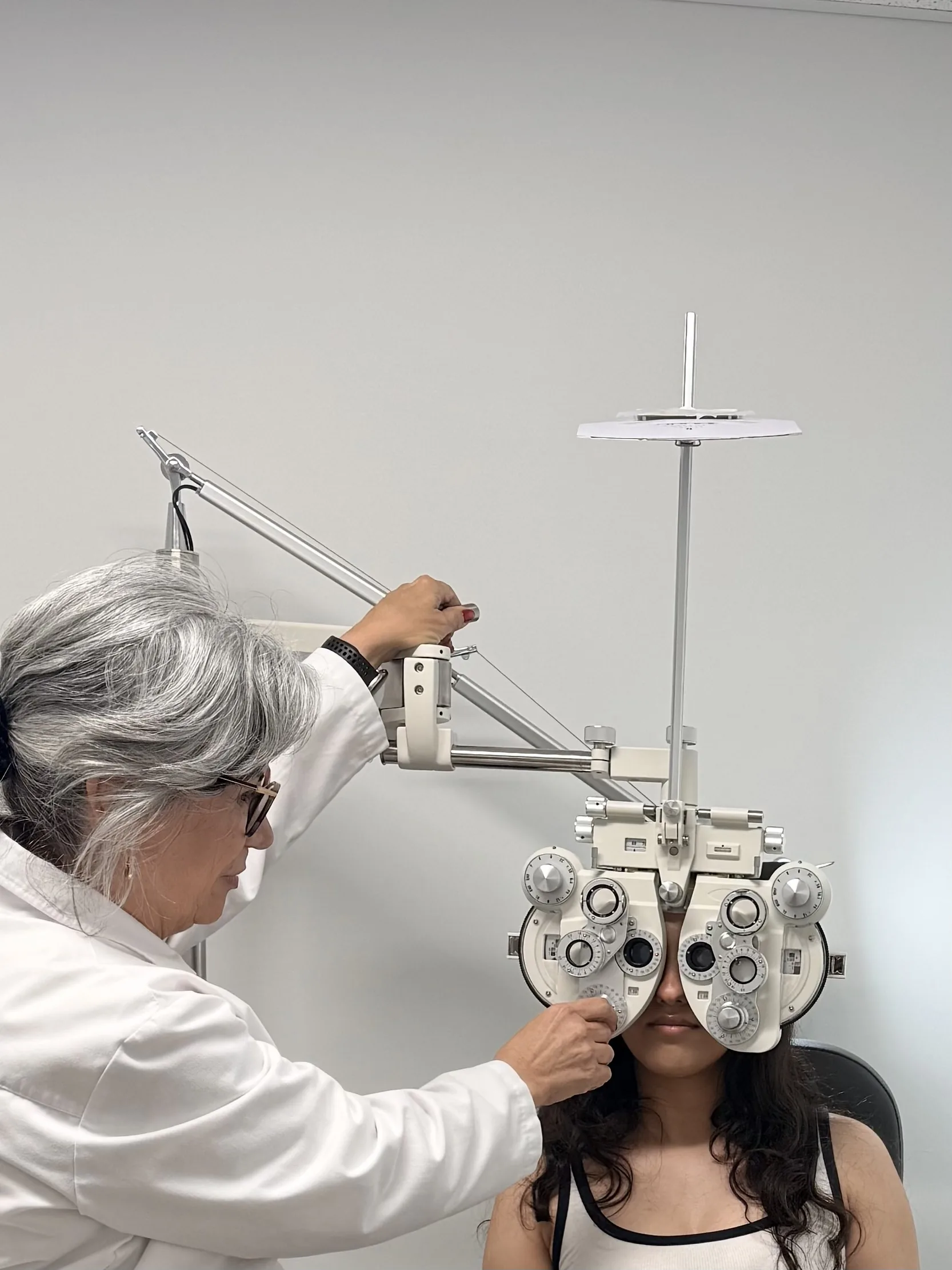 Dr. Roxanna Gangi, optometrist in Ontario, performing a refraction with a phoropter during a comprehensive eye exam